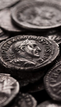 Close-up shot of coin of roman emperor Maximinus among other coins, selective focusing